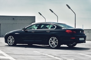 Sleek black luxury sedan parked with city skyline at dusk.