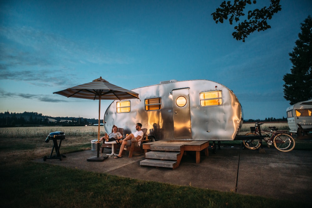 man and woman sitting in front of RV trailer