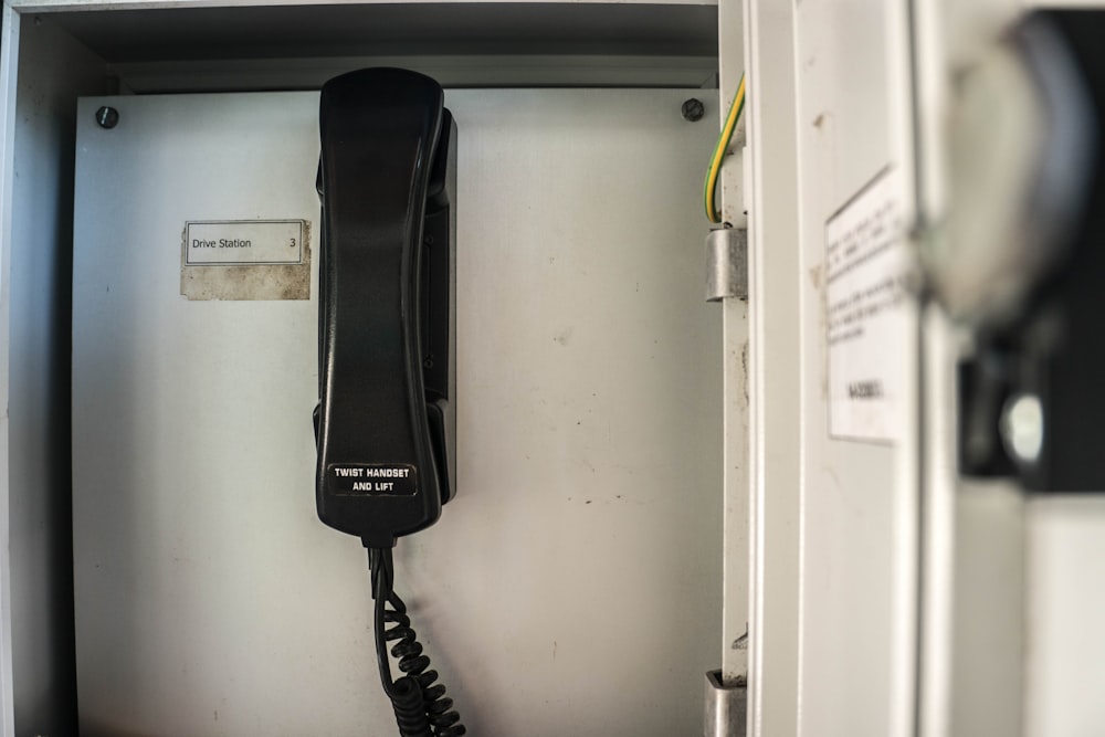 selektives Fotografieren eines schwarzen IP-Telefons in der Nähe einer weißen Wand