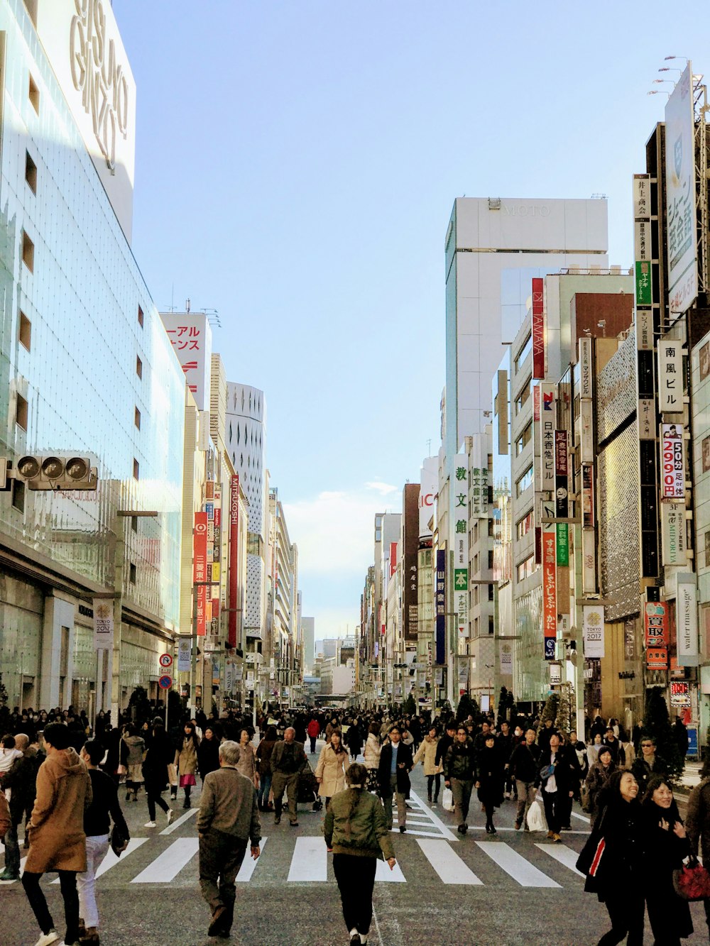 Persone che camminano per strada tra gli edifici sotto il cielo blu