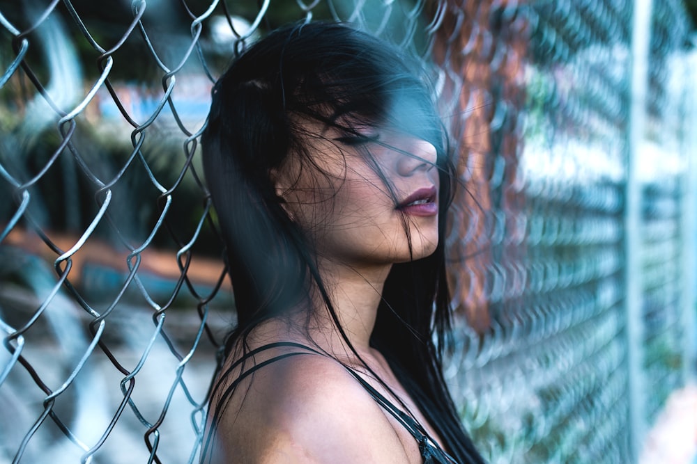 woman leaning on cyclone fence