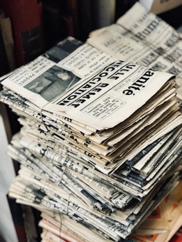 bundle of newspaper on table von Mr Cup / Fabien Barral (https://unsplash.com/@iammrcup)