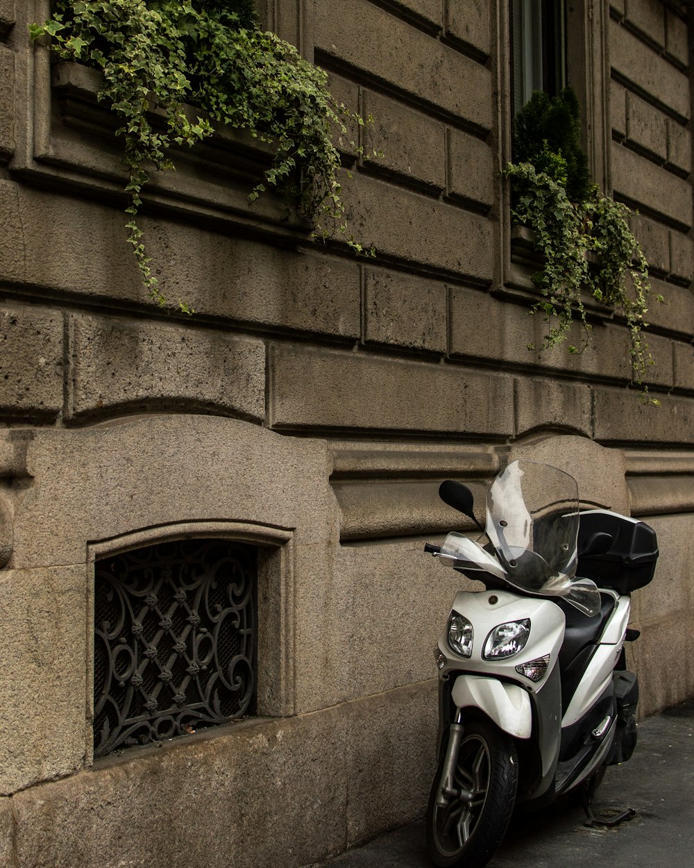 white and black touring motor scooter parked on sidewalk