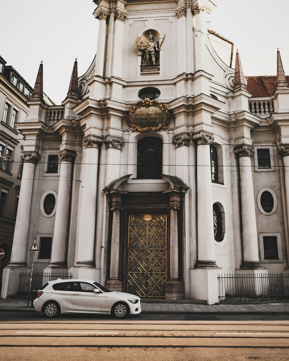 white 3-door hatchback near white concrete church at daytime