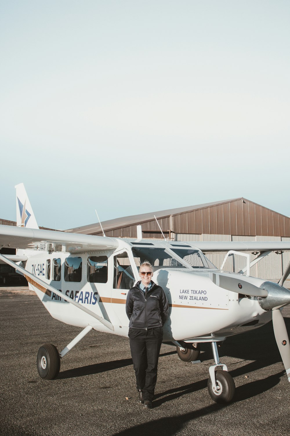 Frau steht, während sie sich an ein Flugzeug lehnt