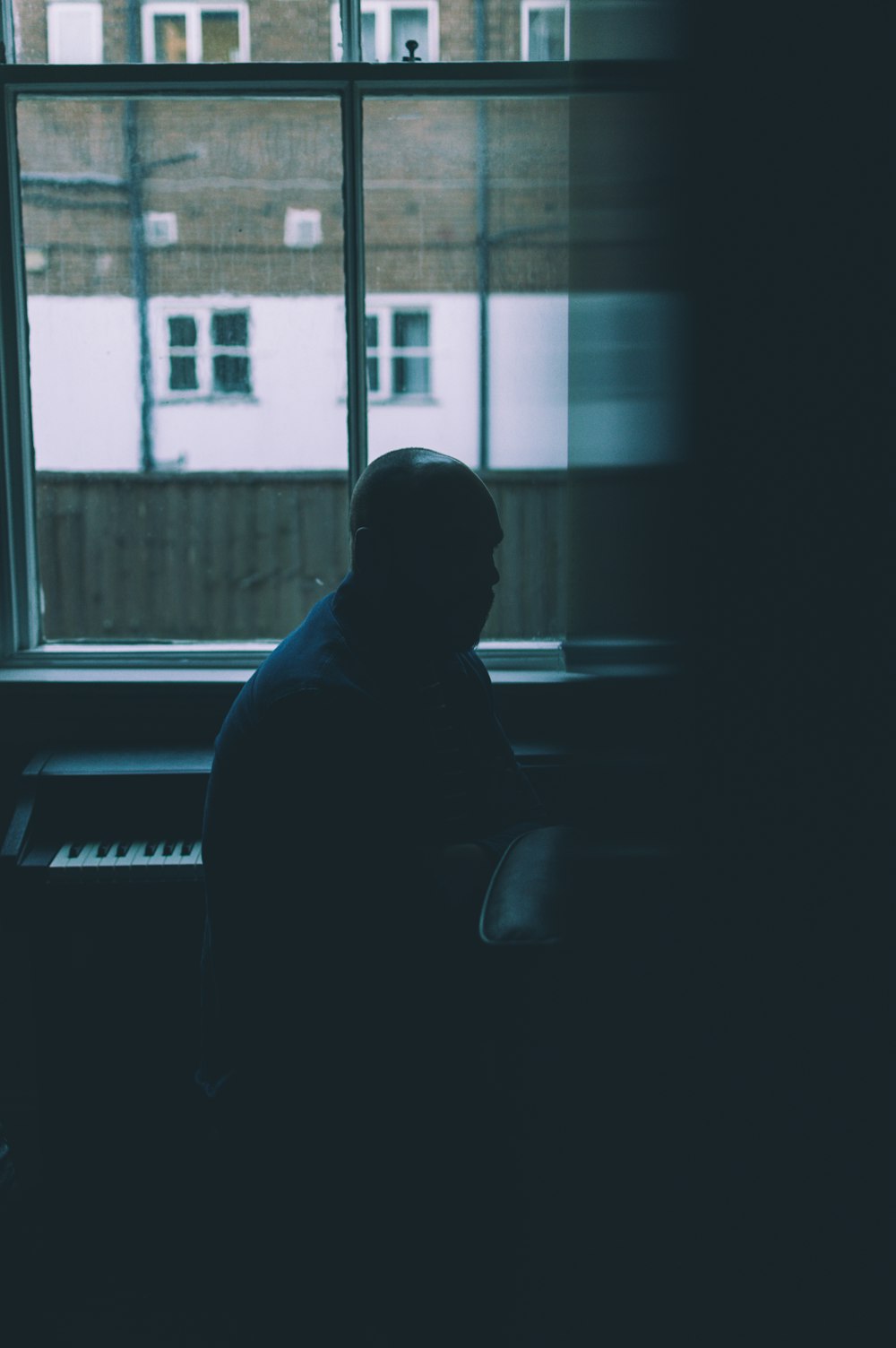 homem sentado perto do piano dentro da sala