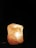 A large, translucent rock salt lamp is illuminated from within, casting a warm and soothing glow. The surface is rough and the color ranges from white to pale orange with scattered darker spots.