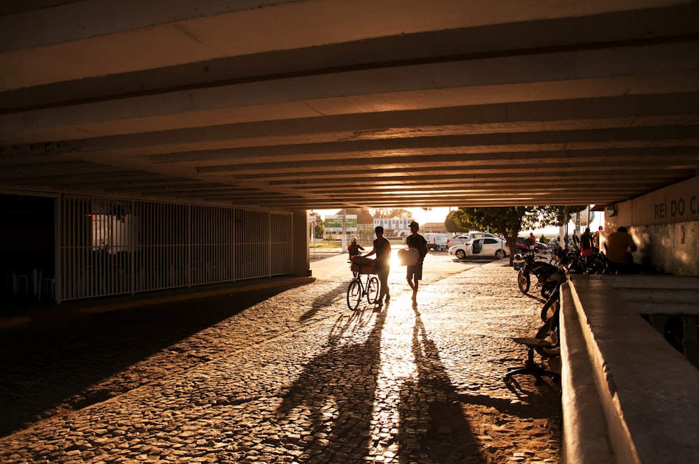 silhouette of two person walking under bridge