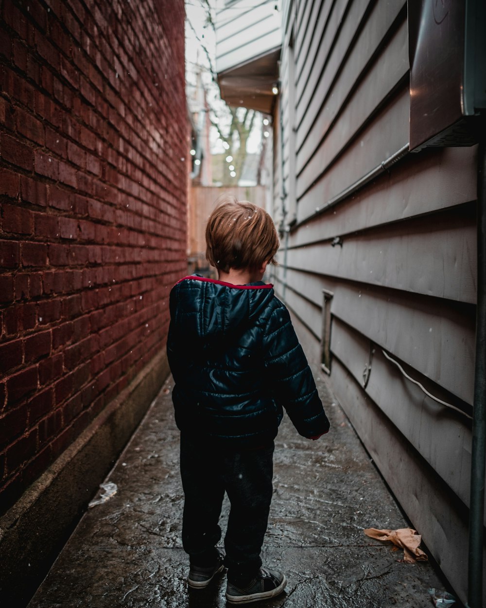 Fotografía de enfoque superficial de niño pequeño en callejón