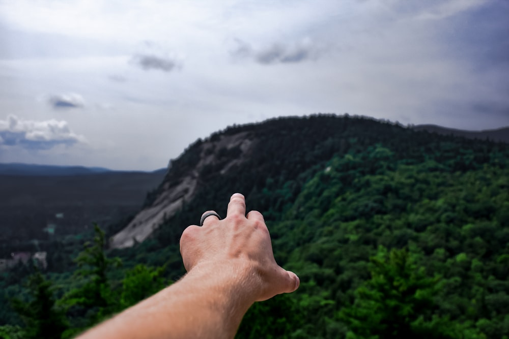 person pointing mountain with finger