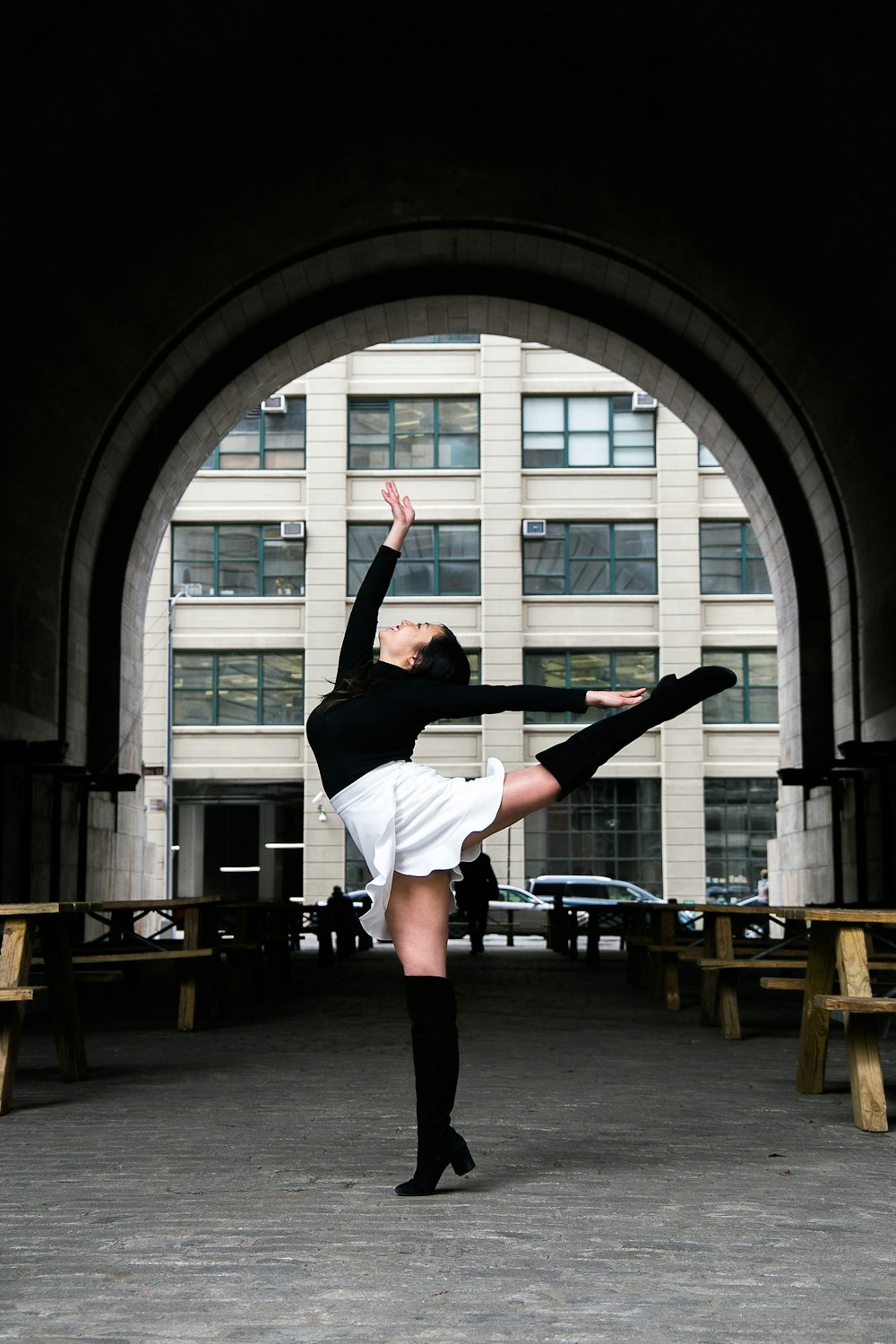 woman wearing black top and white skirt standing on right foot with pointed toes