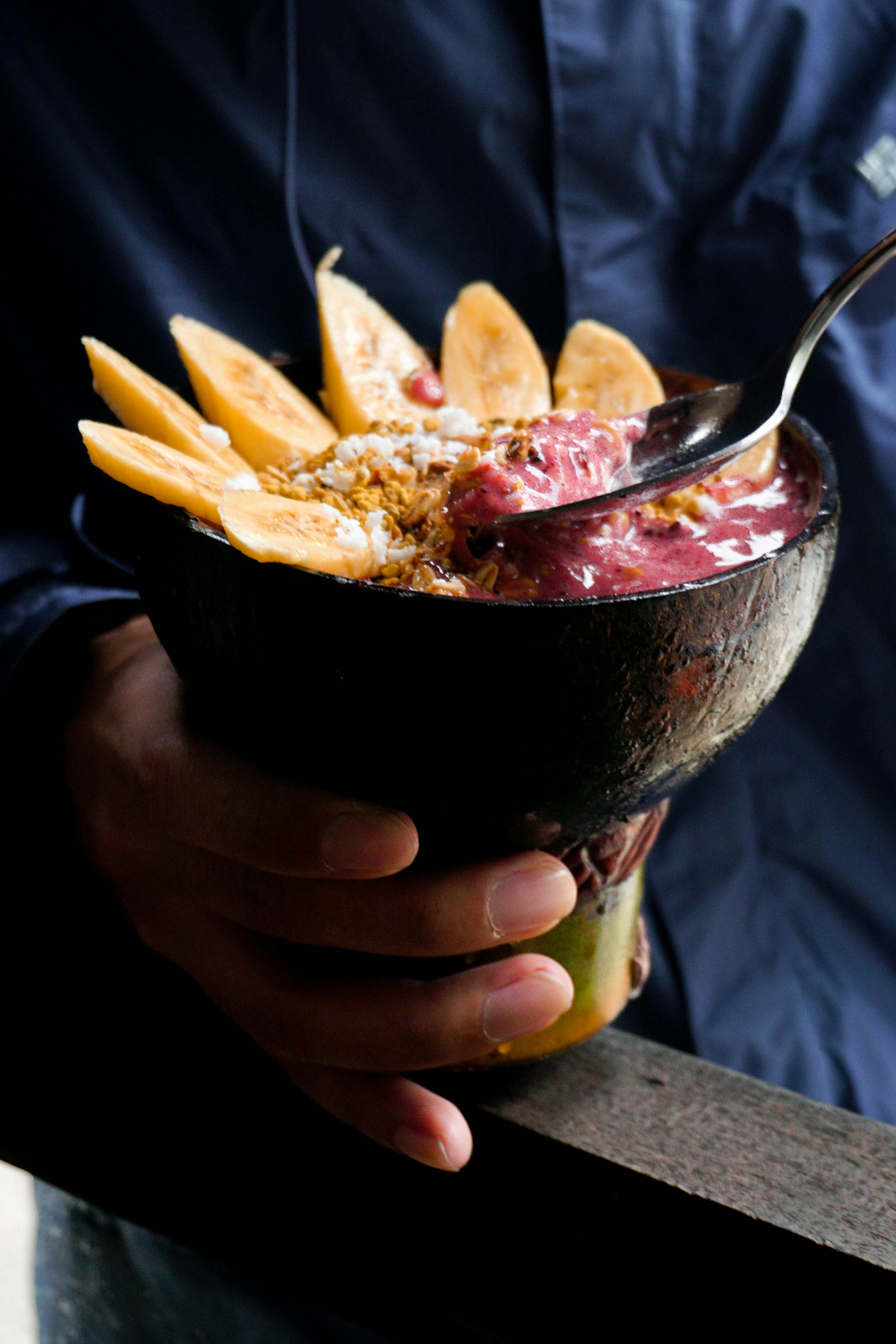 Power açaí bowl with banana slices, thick granola layer, peanut butter drizzle and chia seeds, health food photography