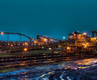 lighted brown concrete buildings near body of water at nighttime