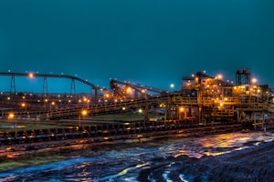 lighted brown concrete buildings near body of water at nighttime