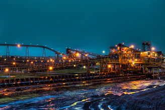 lighted brown concrete buildings near body of water at nighttime