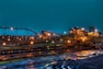 lighted brown concrete buildings near body of water at nighttime