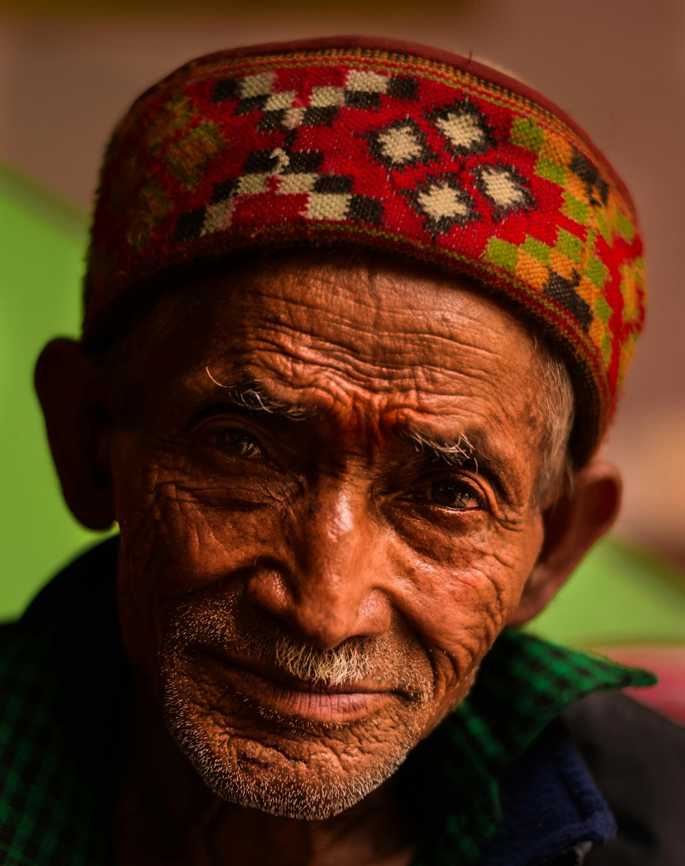 close-up photo of man wears red and multicolored traditional headdress