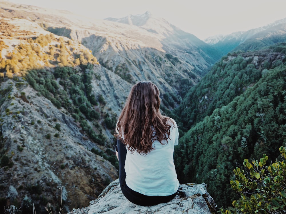 woman sitting on mountain peak