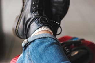 Detail shot of polished leather boots paired with rolled-up denim jeans.