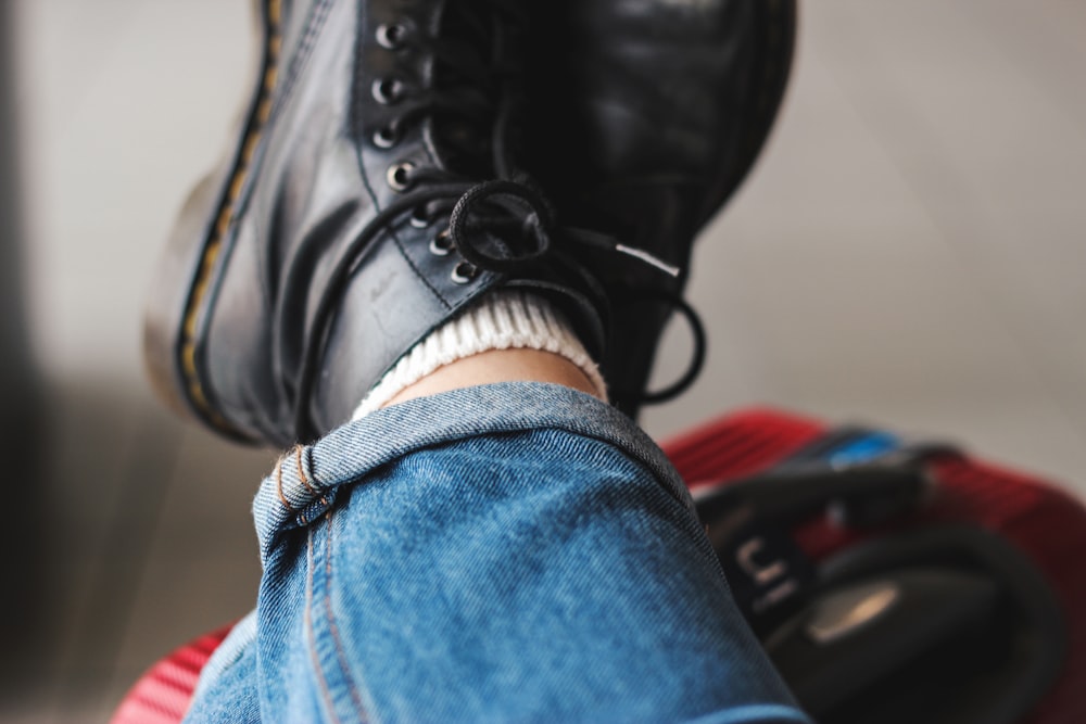 person wearing a pair of black work boots and blue jeans