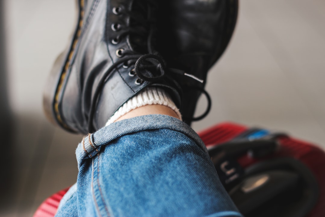 person wearing a pair of black work boots and blue jeans, waiting