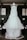 A white wedding dress with lace details is hanging on a wooden frame in a room. The dress has a full tulle skirt and intricate lace bodice, creating an elegant and romantic appearance.