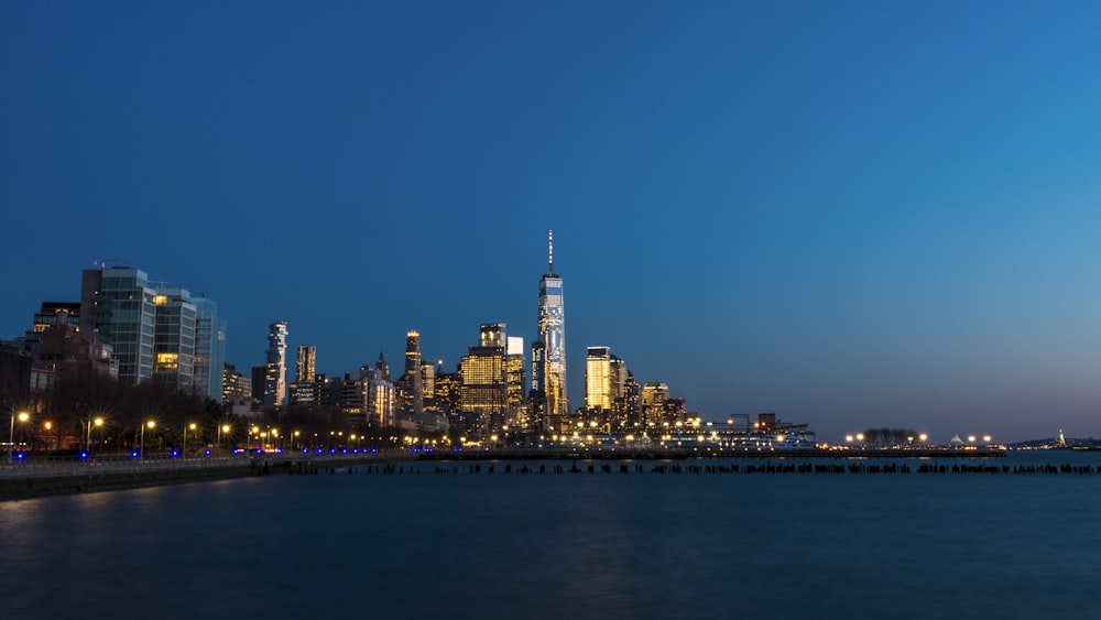 lighted concrete buildings front of sea at night time