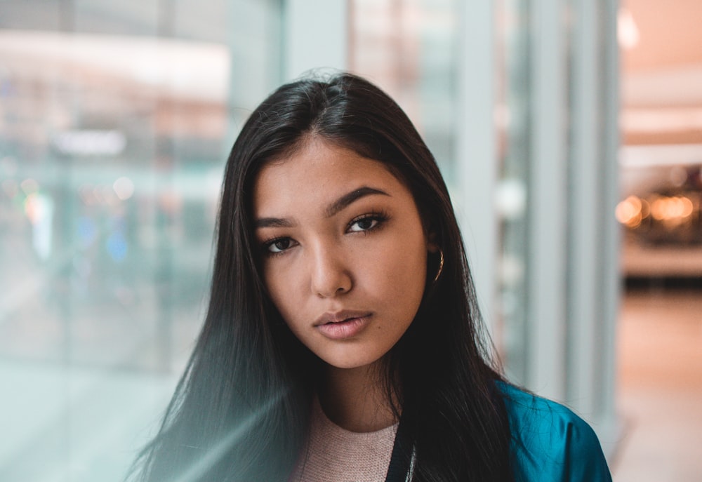 woman in gray shirt standing beside glass