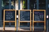 three wooden chalkboard in front of glass panel door
