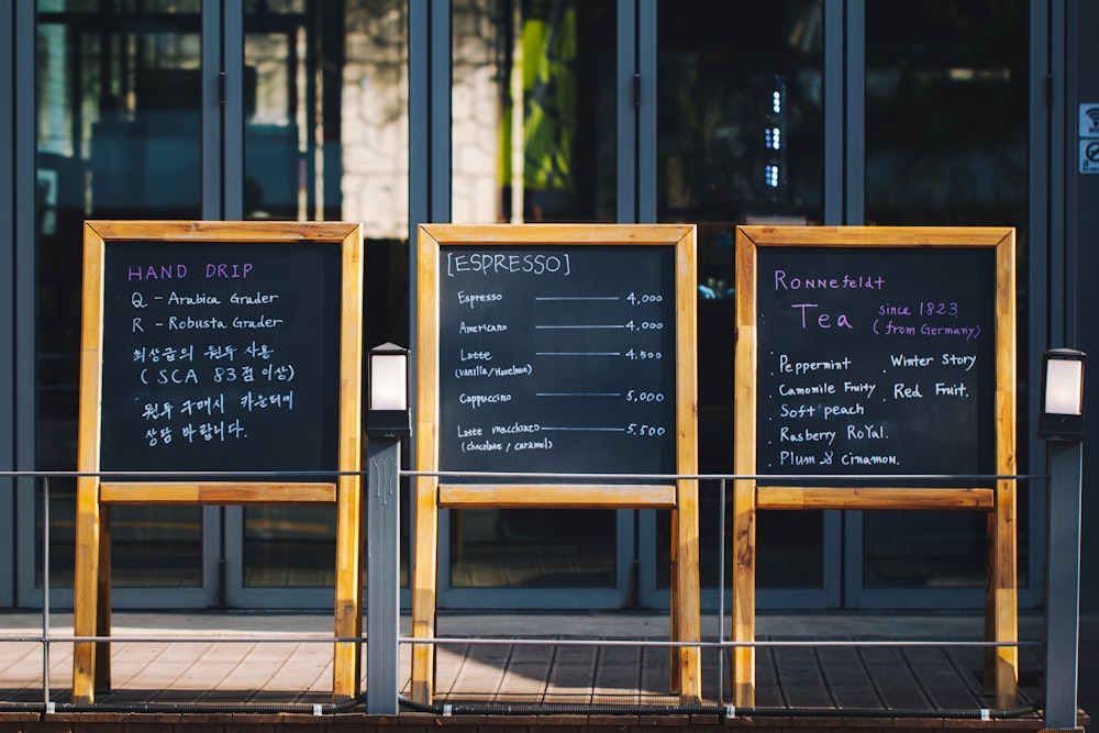 three wooden chalkboard in front of glass panel door