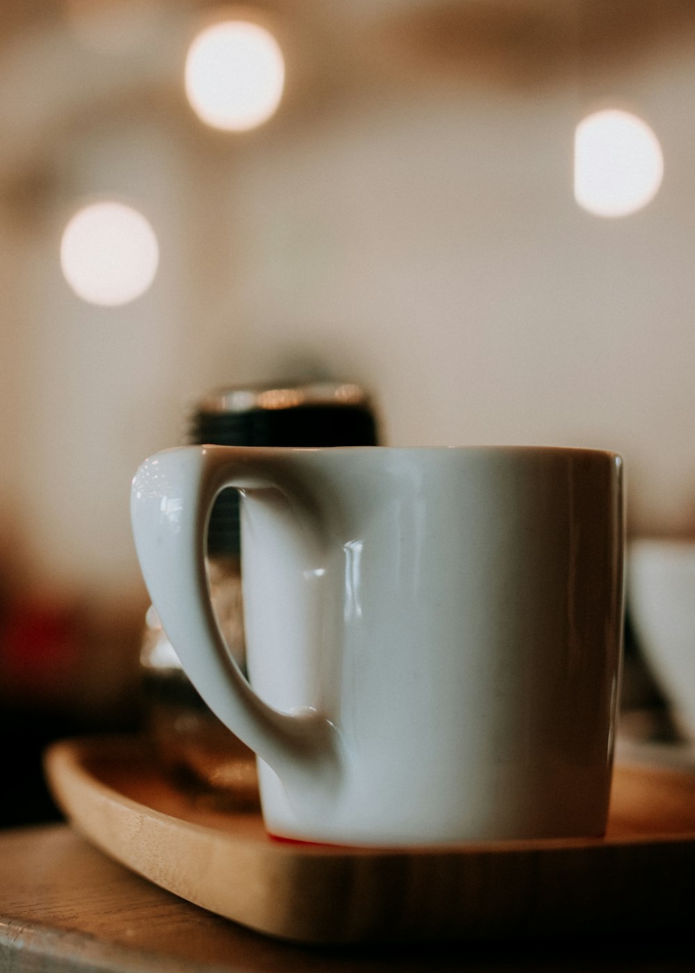 Fotografia de foco raso da caneca de cerâmica na bandeja de madeira