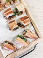 A variety of colorful sandwiches arranged on a wooden platter.