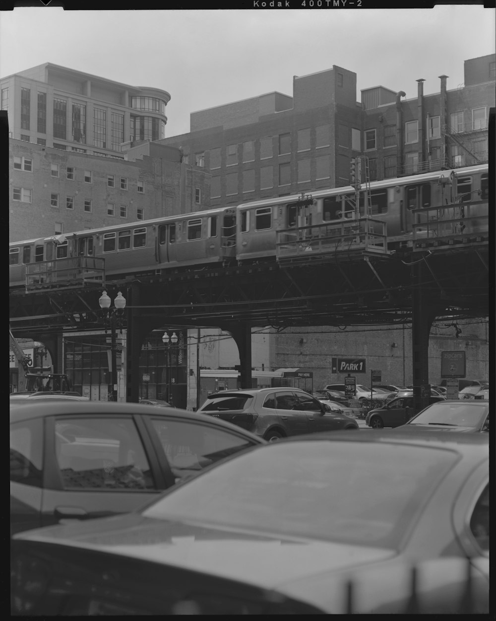 grayscale photography of cars under the trail rails