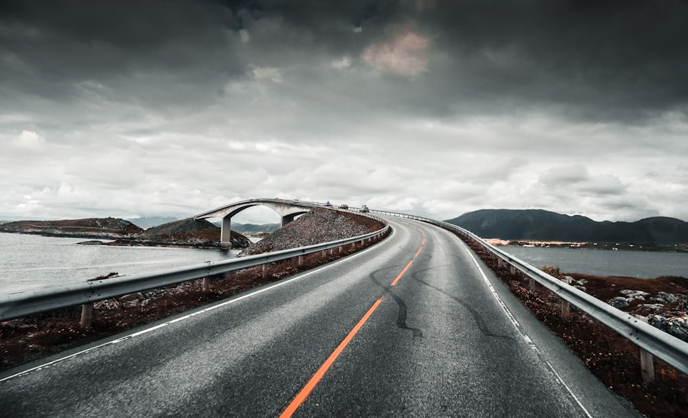 photo of asphalt road near body of water