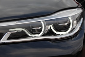 A close-up view of a modern car headlight featuring a sleek design with LED light strips and reflective surfaces.