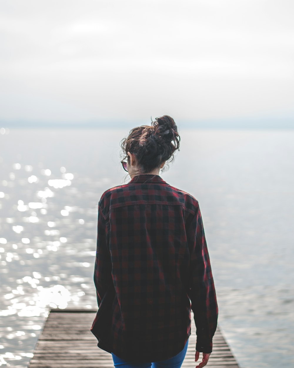 woman wearing black and red gingham walking on wooden dock