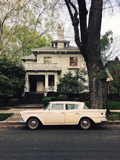 white sedan parked in front of house near tree