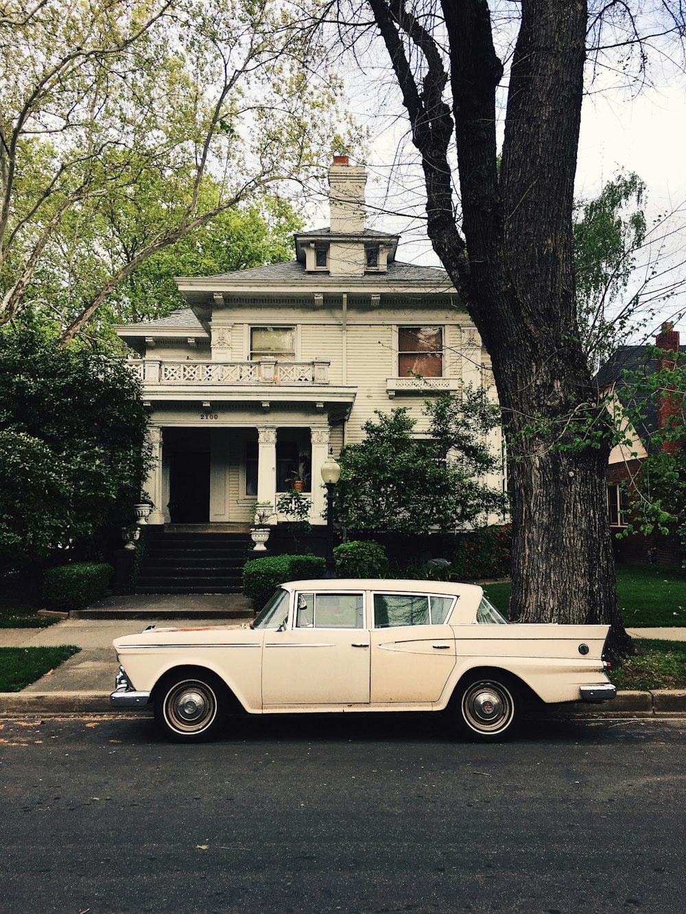 white sedan parked in front of house near tree