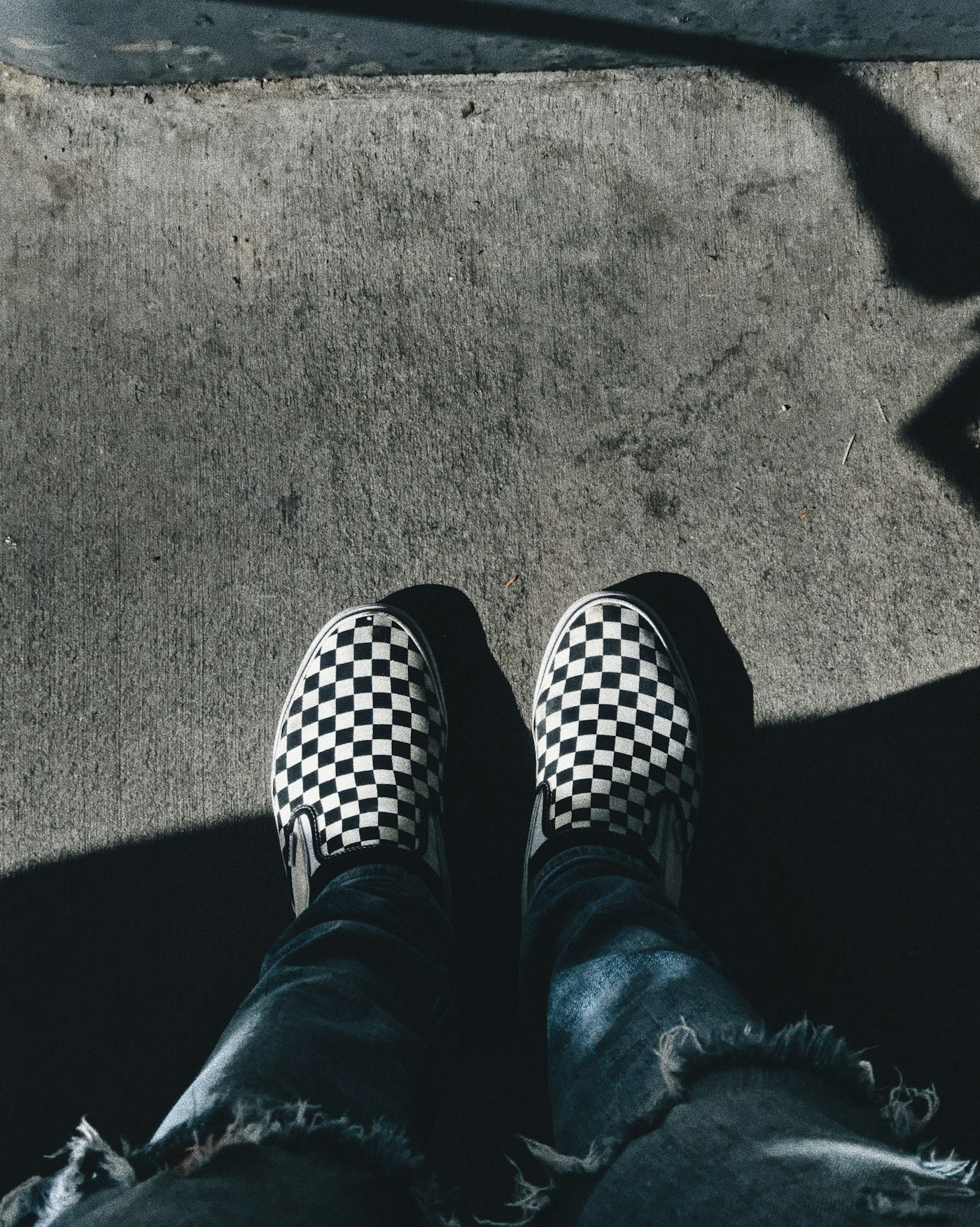 Overhead view of a person wearing black and white checkerboard slip-on shoes
