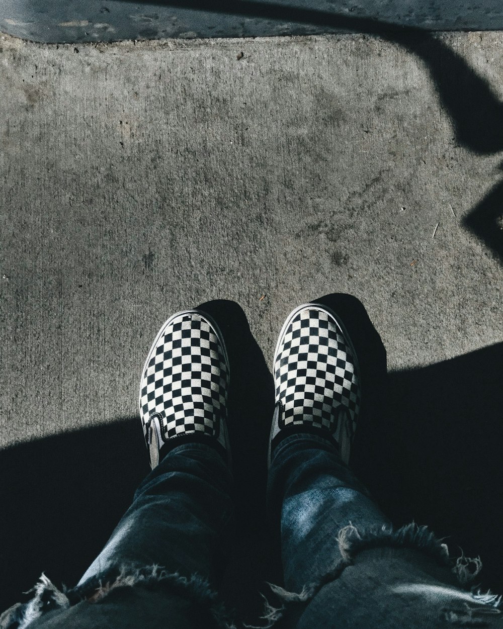 person standing while showing pair of black-and-white checkered shoes