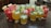 An assortment of colorful beverages is arranged on a granite countertop. The drinks are presented in various types of glassware and garnished with fresh fruits such as watermelon slices, lime wedges, and mint leaves. Ice cubes are visible in some of the glasses, suggesting they are refreshing and cold.