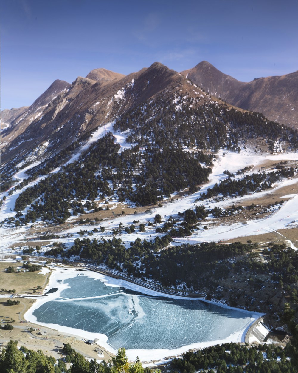 body of water beside trees near mountain