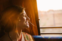 A serene woman sitting quietly in prayer by a sunlit window surrounded by nature.