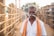 man standing next to brown wall