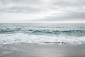 A calm ocean view with gentle waves and a sandy shore.