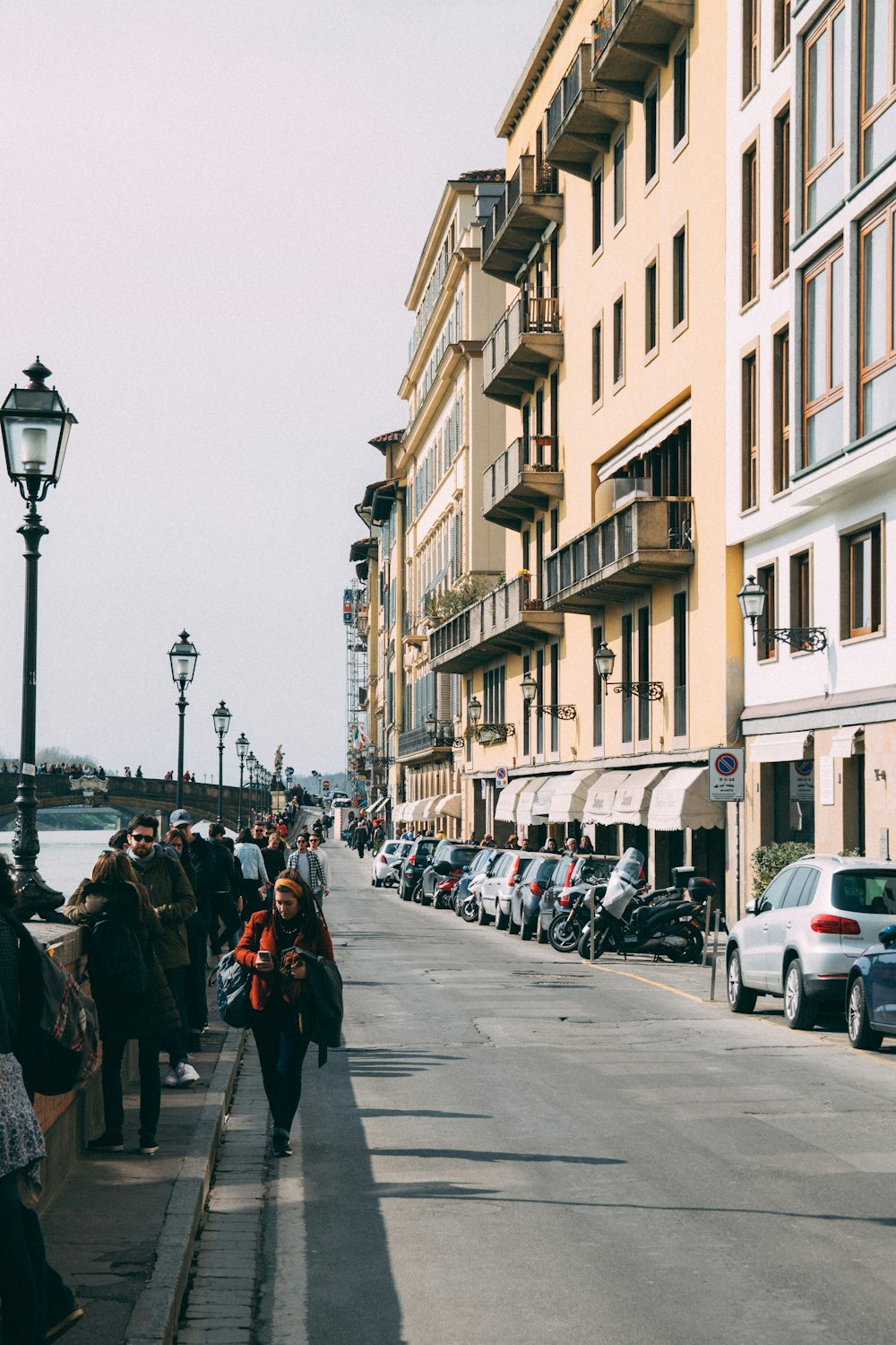 group of people walking near buildings and body of water during daytime