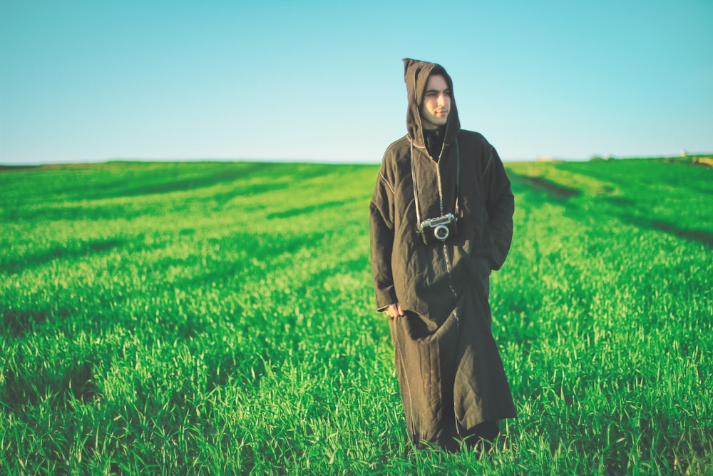 homme en robe marchant sur le champ d’herbe verte