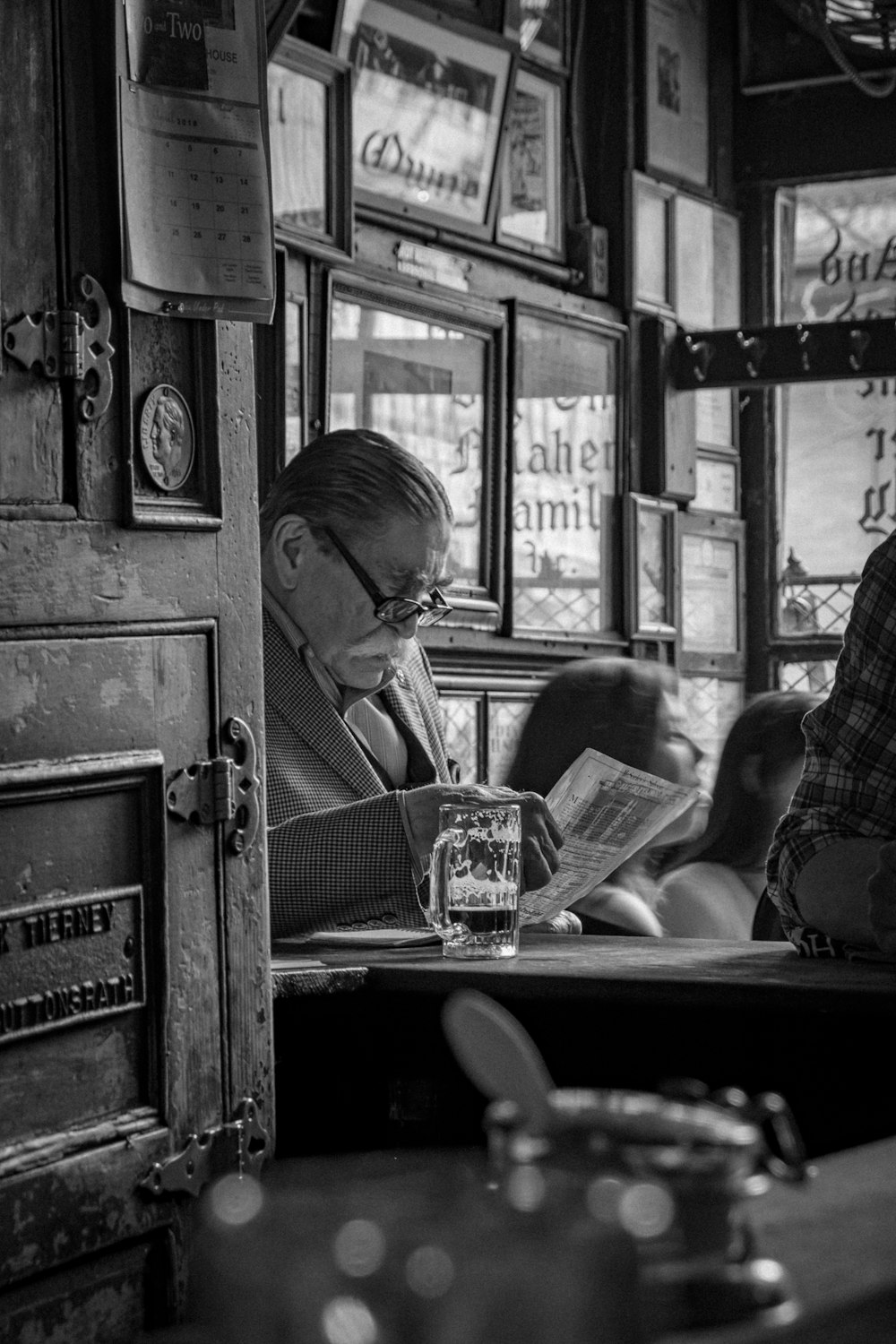 greyscale photo of man sitting while reading newspaper