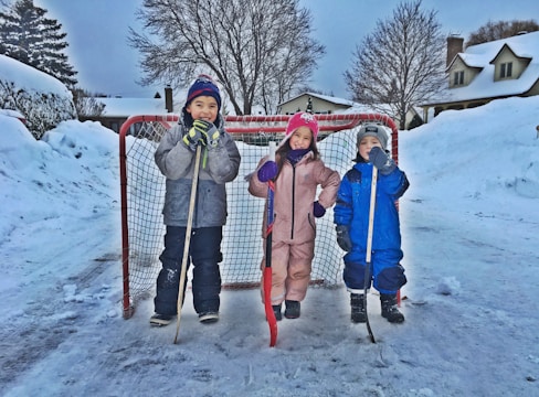 Children playing hockey on the outdoor arena during winter.