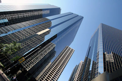 Modern business district with tall glass skyscrapers reflecting sunlight, no branding visible.